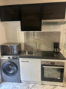 a kitchen with a sink and a washing machine at Deux pièces au centre-ville proche des plages et centres commerciaux in Saint-Laurent-du-Var