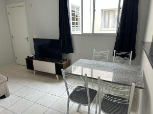 une table et des chaises dans un salon avec une télévision dans l'établissement Apto aconchegante de 2 quartos, à Contagem