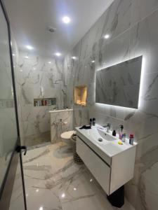 a white bathroom with a sink and a toilet at Charmante maison de ville in Bin Rhilouf +9 photos