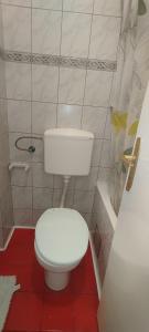 a bathroom with a white toilet and a red floor at Centar Novi Sad in Novi Sad