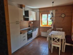 a kitchen with white cabinets and a table and a dining room at Apartment Vila Lokve in Lokve