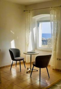 two chairs and a table in a room with a window at Apartments Zlata In the Heart of the Old Town, Close to the Beach in Rab