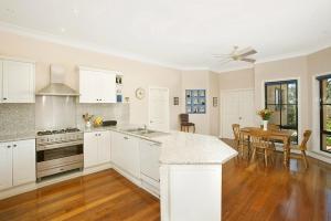 a kitchen with white cabinets and a table and a dining room at Stately Bowral Designer Home in Bowral