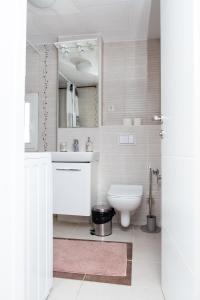 a white bathroom with a toilet and a sink at The Serene Oasis Red in Sarajevo +2 photos