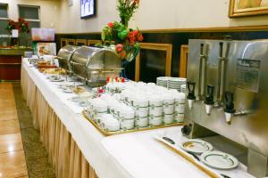 a buffet line with white cups and plates of food at Prince Hotel in Ribeirão Preto