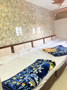 two twin beds in a room with a stone wall at Hotel Shree dhan Laxmi palace in Jāmb