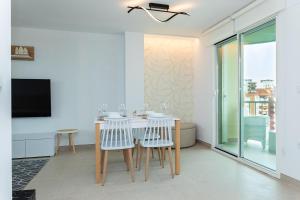 Playa de GandiaにあるLaraMar Solo Familias Apartamento vistas al marのテーブルと椅子とテレビのあるダイニングルーム