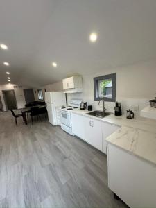 kuchnia z białymi szafkami i stołem w obiekcie Cozy 4-Bedroom Cottage #2 in Innisfil w mieście Innisfil +11 zdjęć