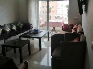 a living room with couches and tables and a large window at Les terrasses 2 in Mansouria +1 photo
