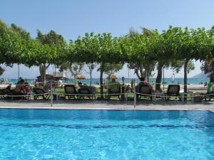 Porto Fico Hotel في فاسيليكي: حمام سباحة مع أشخاص يجلسون في الكراسي بجوار المحيط