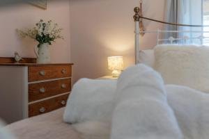 a bedroom with a bed and a dresser with a lamp at Angel Cottage in Swanage