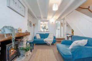 a living room with blue couches and a fireplace at Angel Cottage in Swanage