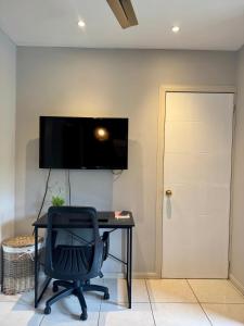 a desk with a chair and a television on a wall at Pipas Apartment I Walk to the beach in Tamarindo