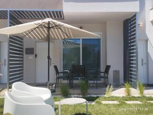 a patio with a table and chairs under an umbrella at Jason Holidays Skala Rachoniou in Skala Rachoniou