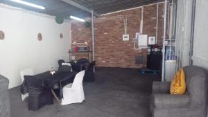 a room with a table and chairs and a brick wall at The Croc Backpackers in Springs