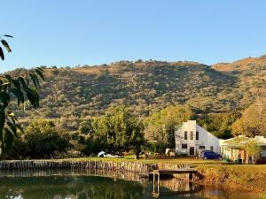 a house and a lake with a mountain in the background at La Ronel Guest Farm in Roossenekal
