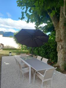 a table and chairs with a black umbrella at Maison de maître in Argelès-Gazost