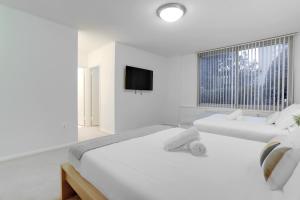 a white bedroom with two beds and a tv at Spacius Apt W Excellent Amenities in Arlington