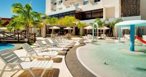une piscine avec des chaises longues et un complexe hôtelier dans l'établissement Le Jardin - Via Caldas, à Caldas Novas