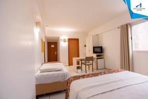 une chambre d'hôtel avec deux lits et un bureau dans l'établissement Le Jardin - Via Caldas, à Caldas Novas