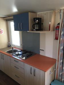 a small kitchen with a stove and a sink at violette mobil home capacité 4 personnes climatisé in Vic-la-Gardiole