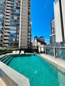 a swimming pool on top of a building with tall buildings at Apto completo em Pinheiros. Estilo e Conforto! in Sao Paulo