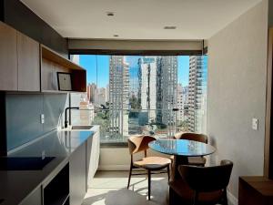 a kitchen with a glass table and a view of a city at Apto completo em Pinheiros. Estilo e Conforto! in Sao Paulo
