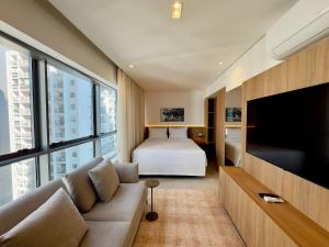 a hotel room with a bed and a couch and a television at Apto completo em Pinheiros. Estilo e Conforto! in Sao Paulo
