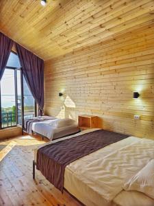 two beds in a room with a wooden wall at Royal Ak-Terek Issyk-kul in Ak-Terek