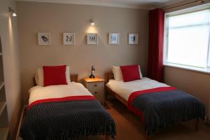 two beds in a room with a window and pictures on the wall at Stylish 4Bed Cottage with parking near town and beach in Lyme Regis