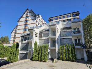 ein hohes weißes Gebäude mit Bäumen davor in der Unterkunft Maslacak Lila Apartment in Zlatibor