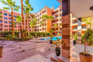 une cour d'appartement avec des palmiers et une piscine dans l'établissement Top localisation, neuf, Piscine et une vue balcon, à Marrakech