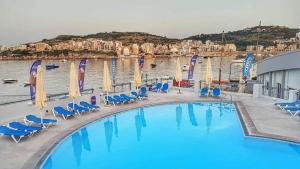 ein großer Pool mit Stühlen und einem Wasserkörper in der Unterkunft Honeymoon Seaview in St Paul's Bay