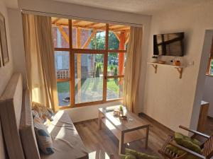 a living room with a large window and a table at Vikendica Trenutak - Vikendica na Drini in Loznica