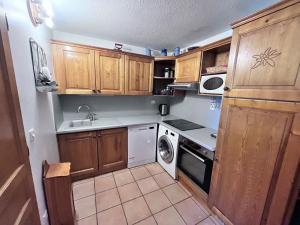 a small kitchen with wooden cabinets and a dishwasher at Appartement Duplex 10-12 Pers. avec Balcon, à 20m des Pistes - Val Cenis - FR-1-508-69 in Lanslevillard