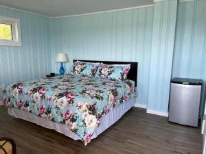 a bedroom with a bed with a floral comforter at Pete's Lakefront Motel, LLC in Geneva