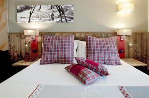 a bed with red and white pillows on it at Olimpia Hotel in Bormio