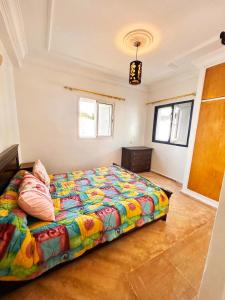 a bedroom with a bed with a colorful comforter at Palm beach in Mansouria in O Ben Slimane