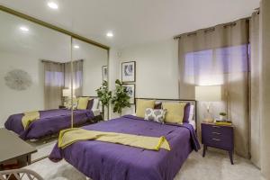 a bedroom with two beds with purple sheets and a mirror at Beryl Bungalow in San Diego
