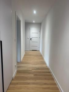 an empty hallway with white walls and wood floors at Apartament Maksa in Ostróda