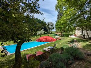 a garden with a pool and a red umbrella at Le Ptit Manoir des Miroirs beautifull 4 star rated gîte near Cognac, private heated pool, 4 bedrooms each with 1 large double bed OR 2 singles in Saint-Aulais-la-Chapelle