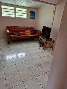 a room with a couch and a laptop on a tiled floor at Charmante maison près de Rivière-Pilote - 65 m² avec terrasse. in Rivière-Pilote