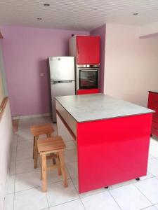 a red island in a kitchen with a refrigerator and stool at Charmante maison près de Rivière-Pilote - 65 m² avec terrasse. in Rivière-Pilote