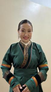 a woman in a green dress with her arms crossed at Tsahar geust house in Ulaanbaatar