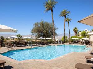 a large swimming pool with chairs and palm trees at The Westin Mission Hills 2BR Apartment with Resort Access in Rancho Mirage