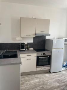 una cucina con elettrodomestici bianchi e mobili bianchi di Les Halles d'Isa et Thomas a Narbonne