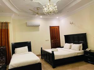 a bedroom with two beds and a chandelier at Executive Galaxy Guest House Islamabad in Islamabad