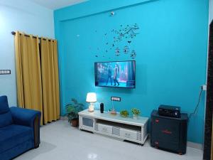 プネにある1BHK Service Apartment 201の青い壁のリビングルーム(テレビ付)