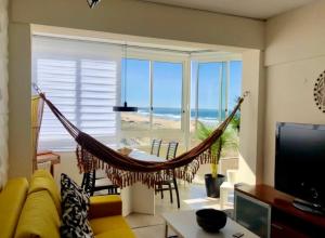 a hammock in a living room with a view of the ocean at Frente práia 8ºandar-parking grátis-surf&naturismo in Costa da Caparica