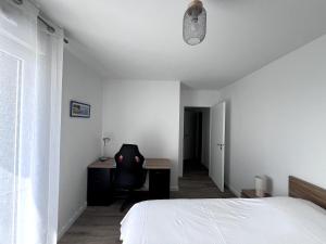 Un dormitorio con una cama, un escritorio y una silla. en Le 30 - Vannes station - 4 pers parking, en Damgan